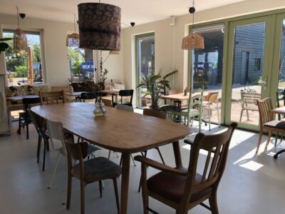 Gezellig binnen zijn aan de stamtafel theehuis vathorst land in zicht Het Theehuis bij Tuinpark Laakzijde Erf, een rustige plek in de natuur waar je kunt ontspannen en genieten van biologische gerechten.